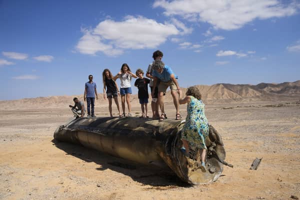 People climb on the debris of an Iranian missile intercepted by Israel, near Arad, southern Israel, on 2 October