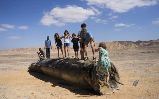 People climb on the debris of an Iranian missile intercepted by Israel, near Arad, southern Israel, on 2 October