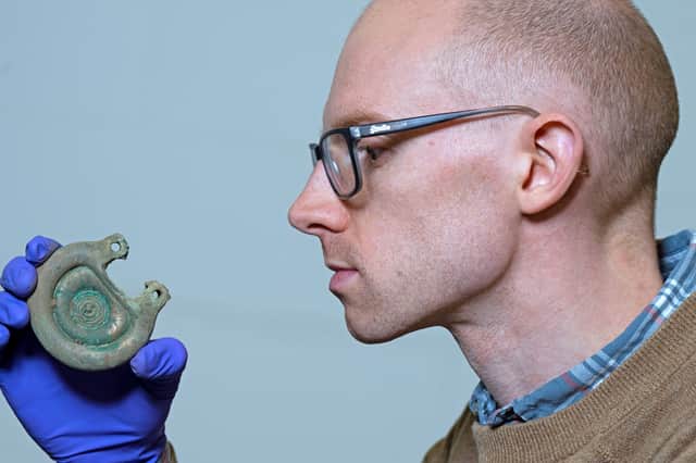 Curator Dr Matthew Knight examining a bronze object from the Peebles Hoard. Photo © Neil Hanna.