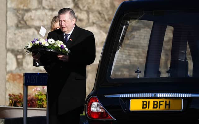Lord Frank Mulholland carries a wreath as he arrives for the funeral service of former first minister Alex Salmond, at Strichen Parish Church, Aberdeenshire