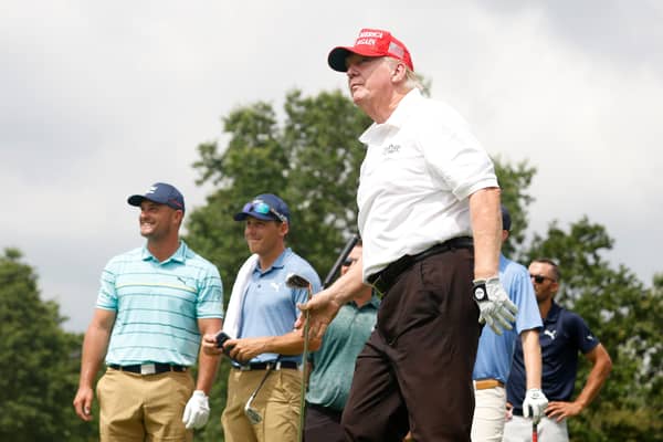 Donald Trump tees off in a LIV Golf event at Trump National Golf Club in New Jersey in 2022 watched by Bryson DeChambeau.
