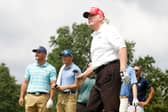 Donald Trump tees off in a LIV Golf event at Trump National Golf Club in New Jersey in 2022 watched by Bryson DeChambeau.