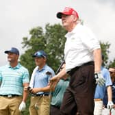 Donald Trump tees off in a LIV Golf event at Trump National Golf Club in New Jersey in 2022 watched by Bryson DeChambeau.