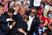 Donald Trump pumps his fist in the air after being wounded in an assassination attempt during the US presidential election campaign in Pennsylvania in July