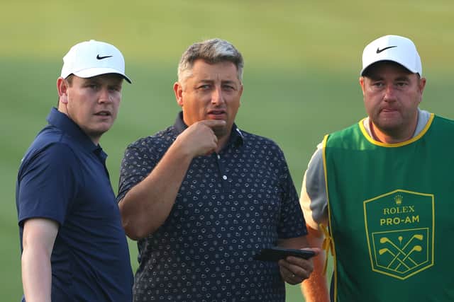 Bob MacIntyre chats with his coach Simon Shanks and caddie Mike Burrow during the Rolex Pro-Am prior to the DP World Tour Championship at Jumeirah Golf Estates in Dubai