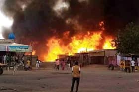 A man watches as a fire rages in a livestock market in al-Fasher, the capital of Sudan's North Darfur state, following an attack by the Rapid Support Forces