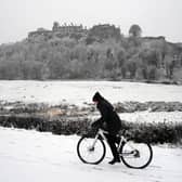 A person rides a bicycle in the snow at Stirling Castle.