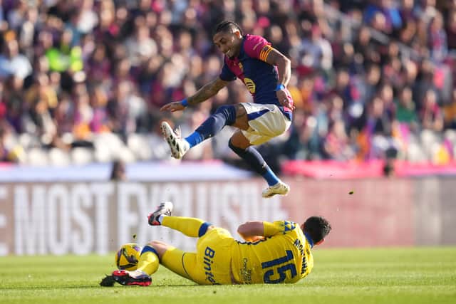 Las Palmas defender Scott McKenna slides in to stop Raphinha.