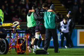 Warriors' Adam Hastings goes off injured following a tackle from Scarlets' Vaea Fifita.