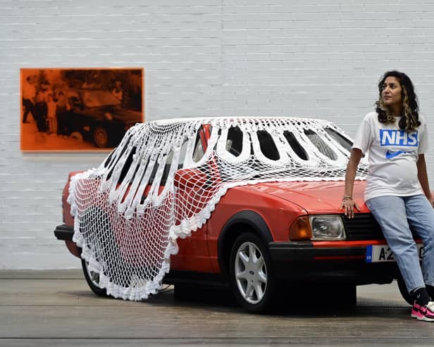 Artist Jasleen Kaur with her installation of a car covered in a giant doily