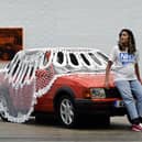 Artist Jasleen Kaur with her installation of a car covered in a giant doily