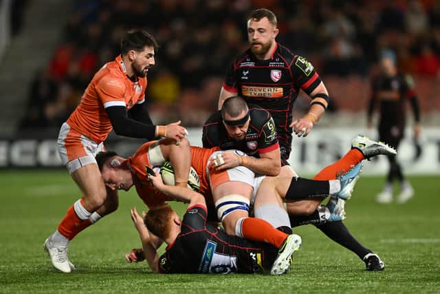 Magnus Bradbury of Edinburgh is tackled by Caolan Englefield and Lewis Ludlow of Gloucester.
