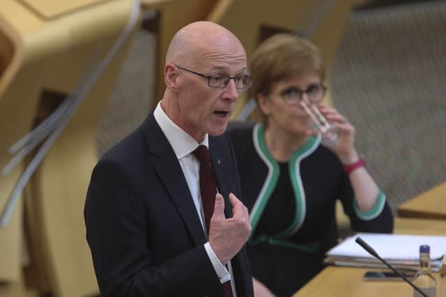 John Swinney speaks at Holyrood, with former first minister Nicola Sturgeon watching on in the background. Picture: PA