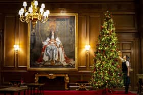 A member of staff putting the finishing touches to the Christmas Tree in the Throne Room at the Palace of Holyroodhouse in Edinburgh, where the exhibition will run. Picture: Jane Barlow/PA Wire 