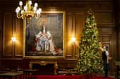 A member of staff putting the finishing touches to the Christmas Tree in the Throne Room at the Palace of Holyroodhouse in Edinburgh, where the exhibition will run. Picture: Jane Barlow/PA Wire 