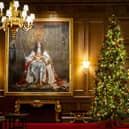 A member of staff putting the finishing touches to the Christmas Tree in the Throne Room at the Palace of Holyroodhouse in Edinburgh, where the exhibition will run. Picture: Jane Barlow/PA Wire 