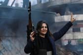 An armed woman flashes the V for victory sign as Syrian Kurds celebrate the fall of capital Damascus to anti-government fighters, in the city of Qamishli
