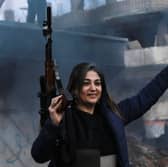 An armed woman flashes the V for victory sign as Syrian Kurds celebrate the fall of capital Damascus to anti-government fighters, in the city of Qamishli