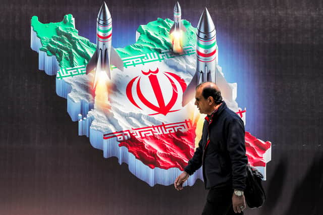 A man walks past a pro-regime banner in central Tehran depicting missiles launching from a map of Iran (Picture: Atta Kenare)