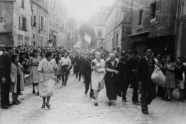 A woman with her baby, whose father is German, and her mother are jeered by crowds in Chartres after having their heads shaved as punishment for collaborating with the Germans.