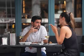 People smoking cigarettes while sitting outdoors at a restaurant, in Soho, London