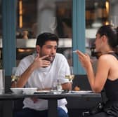 People smoking cigarettes while sitting outdoors at a restaurant, in Soho, London