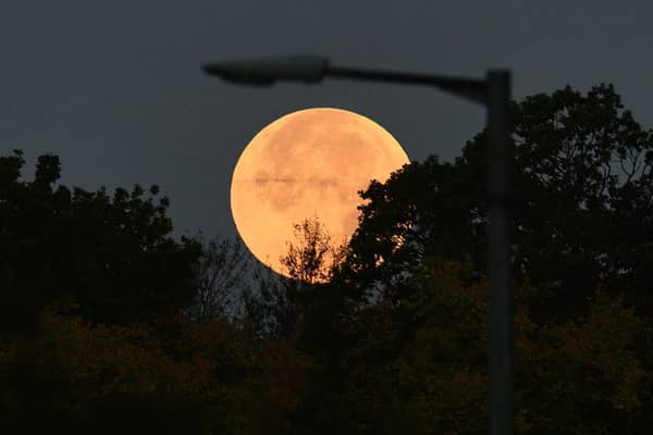 A Harvest moon setting under a lamp post