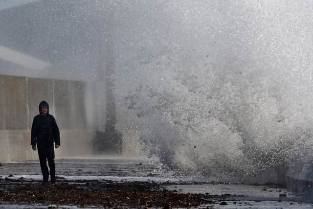 Members of the public walk along a road as waves crash against the sea defences in Saltcoats. Picture: Jeff J Mitchell/Getty Images