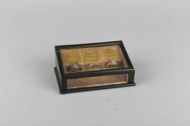 A wooden box containing the wedding ring of Jean Armour, wife of Robert Burns, flanked on each side by two other rings which hold pieces of the couple's hair.