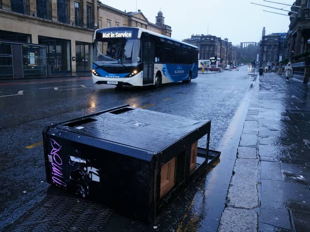A bus drives around bins blown over by the winds from Storm Eowyn on Princes Street.