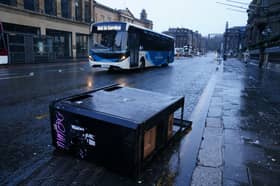A bus drives around bins blown over by the winds from Storm Eowyn on Princes Street.