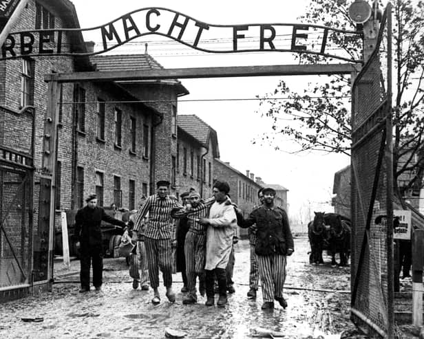 Survivors of the Nazi's Auschwitz-Birkenau camp are led through its infamous gate in 1945 following its liberation by Soviet troops (Picture: Wojtek Laski)