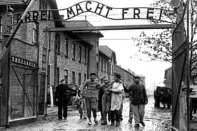Survivors of the Nazi's Auschwitz-Birkenau camp are led through its infamous gate in 1945 following its liberation by Soviet troops (Picture: Wojtek Laski)