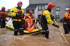 A couple and their dog are rescued from a flooded street in Brechin on October 20, 2023