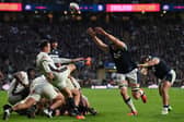 England's scrum-half Alex Mitchell kicks the ball up-field under pressure from Scotland's defence.