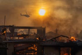 A firefighting helicopter flies over a wildfire as it burns homes in Camarillo, California in November (Picture: David McNew)