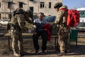 Ukrainian army medics provide first aid to a man at the scene of a Russian Iskander missile attack on a residential building in Kharkiv, Ukraine on Friday (Picture: Diego Fedele)
