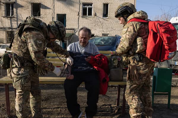 Ukrainian army medics provide first aid to a man at the scene of a Russian Iskander missile attack on a residential building in Kharkiv, Ukraine on Friday (Picture: Diego Fedele)