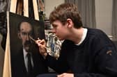 Young artist Connor Draycott puts the finishing touches to a new portrait of James Finlayson.