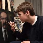 Young artist Connor Draycott puts the finishing touches to a new portrait of James Finlayson.