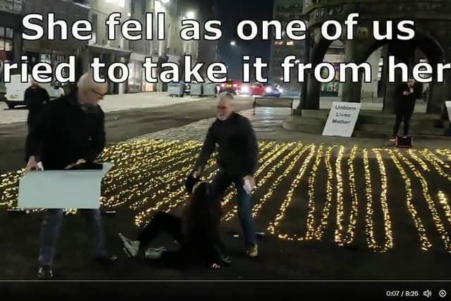 A screengrab of the Scottish Family Party's video, which shows a woman on the ground and a man taking a placard off of her.