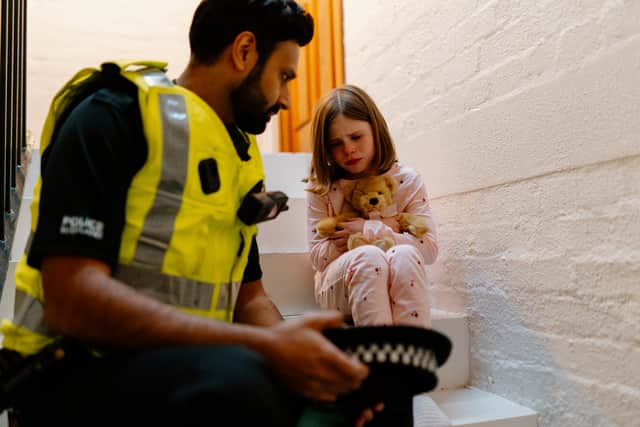 An actor playing a police officer comforts a bereaved child.