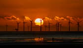 The sun sets behind Burbo Bank wind farm and 'Another Place', an art installation by Anthony Gormley, at Crosby Beach on Merseyside