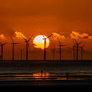 The sun sets behind Burbo Bank wind farm and 'Another Place', an art installation by Anthony Gormley, at Crosby Beach on Merseyside