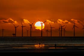 The sun sets behind Burbo Bank wind farm and 'Another Place', an art installation by Anthony Gormley, at Crosby Beach on Merseyside