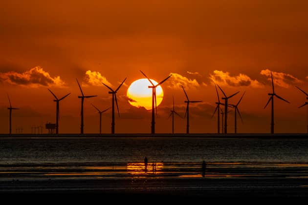 The sun sets behind Burbo Bank wind farm and 'Another Place', an art installation by Anthony Gormley, at Crosby Beach on Merseyside