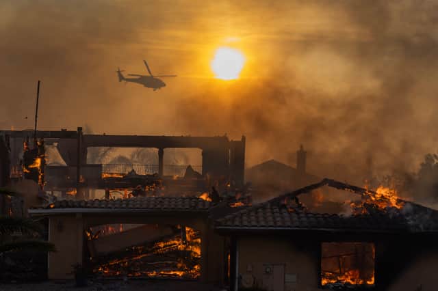A firefighting helicopter flies overhead as a wildfire destroys homes in Camarillo, California, in November last year (Picture: David McNew)