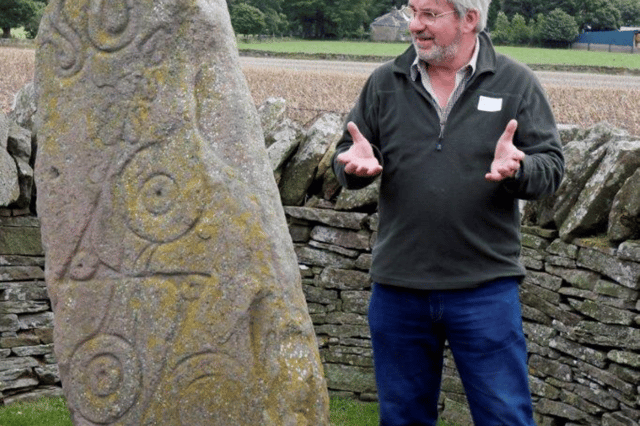 Norman Atkinson, of the Pictish Arts Society, at the roadside stone in Aberlemno. The stone, which is covered in winter, was recently blown over in high winds. PIC: Contributed.