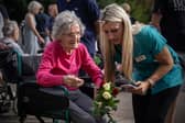 An elderly woman in a wheelchair is assisted by a care-worker as she lays flowers outside Windsor Castle following the death of Queen Elizabeth