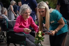 An elderly woman in a wheelchair is assisted by a care-worker as she lays flowers outside Windsor Castle following the death of Queen Elizabeth